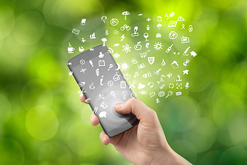 Image showing Hand holding smartphone with icons on green background