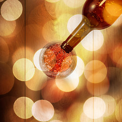 Image showing Red wine pouring into glass from bottle on white wooden table. T