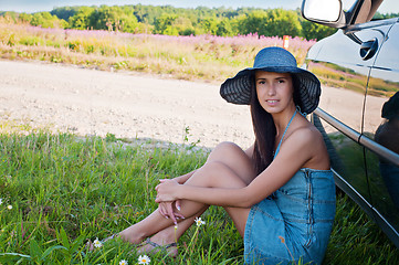 Image showing Happy brunette woman sitting near car