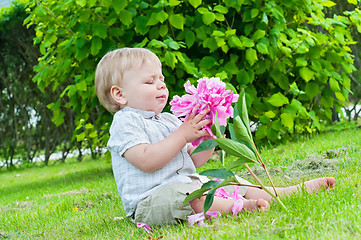 Image showing Small baby boy holding a flower in his hand