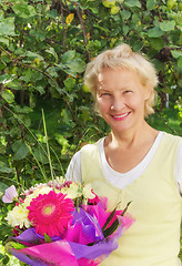 Image showing Portrait of a woman in the garden with a bouquet of flowers