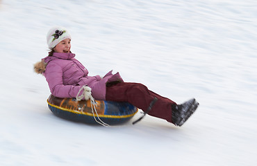 Image showing happy teenage girl sliding down on snow tube