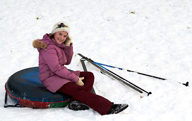 Image showing happy teenage girl having a rest after sliding down on snow tube