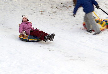 Image showing happy teenage girl sliding down on snow tube