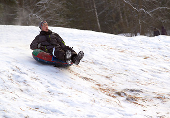 Image showing happy teenage boysliding down on snow tube