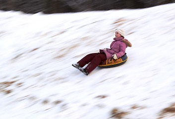 Image showing happy teenage girl sliding down on snow tube