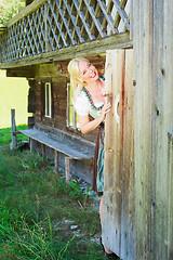 Image showing Young woman in dirndl looks out of the toilet door