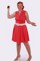Image showing Red-haired woman in red dress 60 years Style and obesity, poses with a Muffin