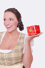 Image showing Young woman in Dirndl and braided hair has a gift on the palm of her hand