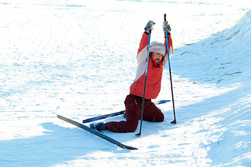 Image showing young beauty girl standing up after drop on snow while skies 