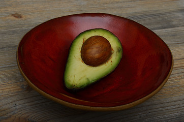 Image showing avocado half on a red ceramic bowl