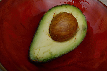 Image showing fresh avocado half on a red ceramic plate