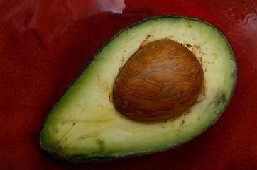 Image showing fresh avocado half on a red ceramic dish