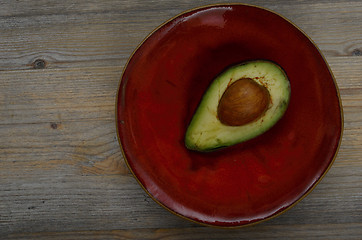 Image showing fresh avocado half on a red ceramic saucer