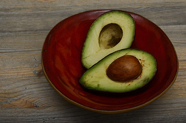 Image showing two halves of avocado on red ceramic bowl