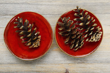 Image showing three pine cones on a red ceramic bowl