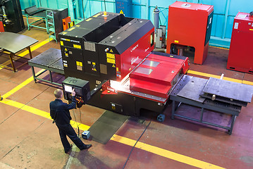 Image showing Worker operates computerized metalworking machine