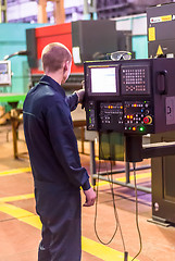 Image showing Worker operates computerized metalworking machine