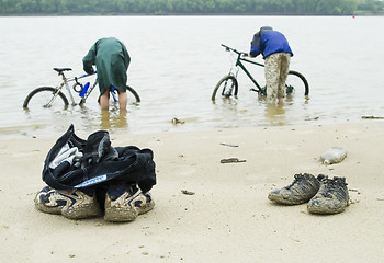 Image showing Dirty cycle tourists wash bicycles from dirt