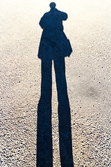 Image showing Elongated Shadow of a Person Standing on the Road