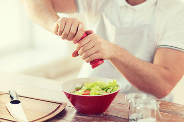 Image showing close up of male hands flavouring salad in a bowl