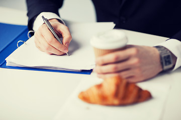 Image showing businessman with coffee writing something