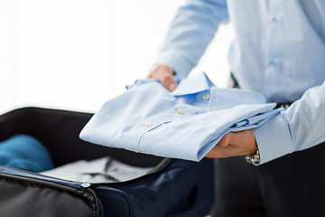 Image showing businessman packing clothes into travel bag