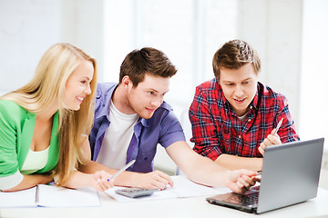 Image showing smiling students looking at laptop at school