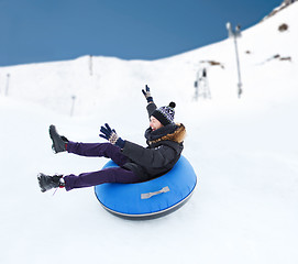 Image showing happy young man sliding down on snow tube