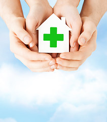 Image showing hands holding paper house with green cross