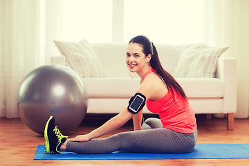 Image showing smiling girl with armband execising at home