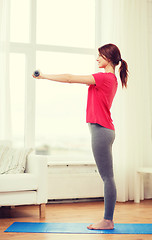 Image showing smiling teenage girl exercising with dumbbells