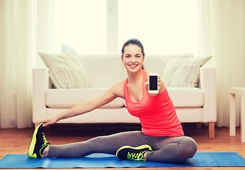 Image showing smiling teenage girl streching on floor at home