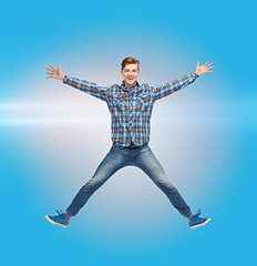 Image showing smiling young man jumping in air