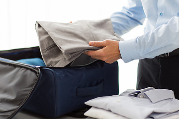 Image showing businessman packing clothes into travel bag