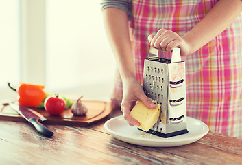 Image showing close up of female hands grating cheese