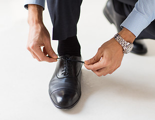 Image showing close up of man leg and hands tying shoe laces