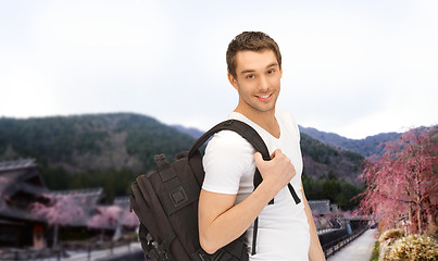 Image showing happy young man with backpack and book travelling