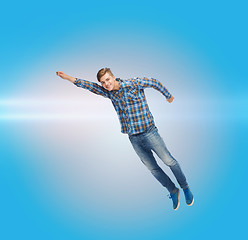 Image showing smiling young man jumping in air