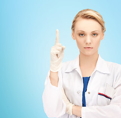 Image showing smiling young female doctor pointing her finger up