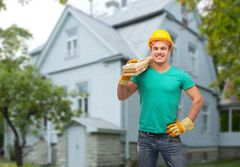 Image showing smiling manual worker in helmet with wooden boards