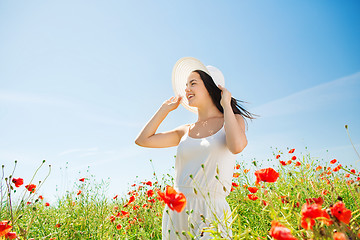 Image showing smiling young woman in straw hat on poppy field