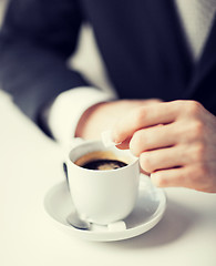 Image showing man putting sugar into coffee