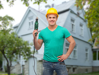 Image showing happy male builder in helmet with electric drill