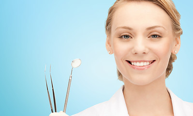 Image showing happy young female dentist with tools