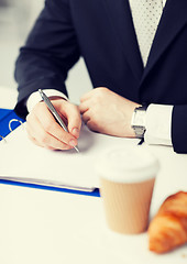 Image showing businessman with coffee writing something