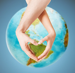 Image showing human hands showing heart shape over earth globe