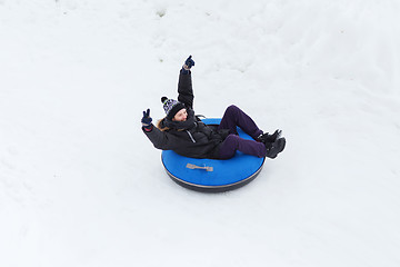 Image showing happy young man sliding down on snow tube