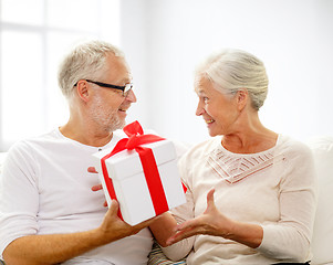 Image showing happy senior couple with gift box at home