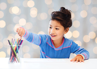 Image showing happy little girl drawing with coloring pencils